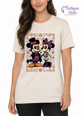 A woman wearing a cream-colored t-shirt with a colorful graphic of Mickey and Minnie Mouse styled as Day of the Dead skeletons, on a white background with a 'Kathyana Studio' watermark.